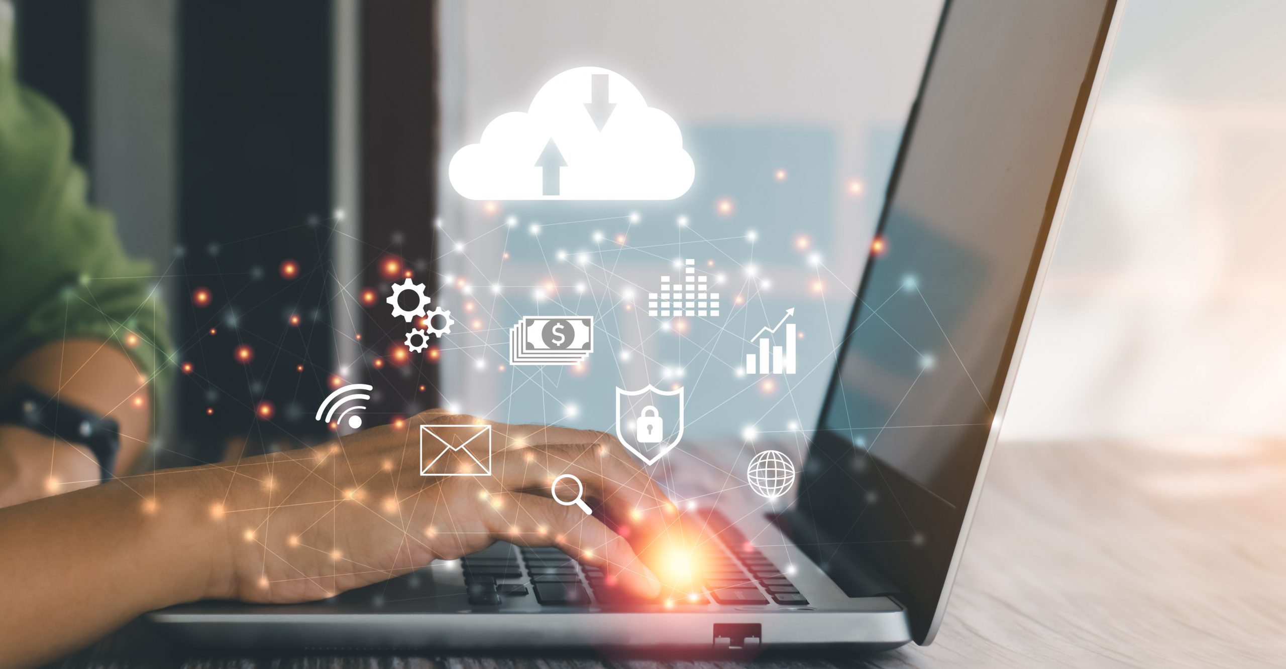 A person types on a laptop keyboard with digital icons of cloud storage, money, security, and other technology symbols floating above, representing various online services and infrastructure functions like uptime availability and backups.
