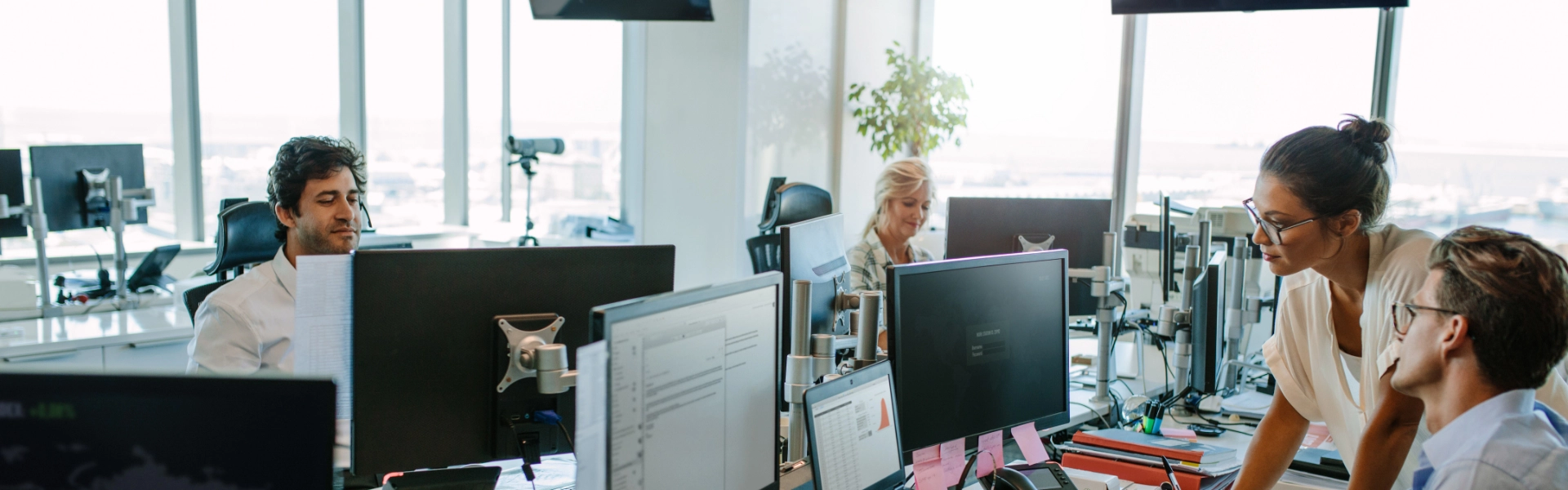 People working at desks with computer monitors in a bright, modern office space, supported by an efficient IT support company.